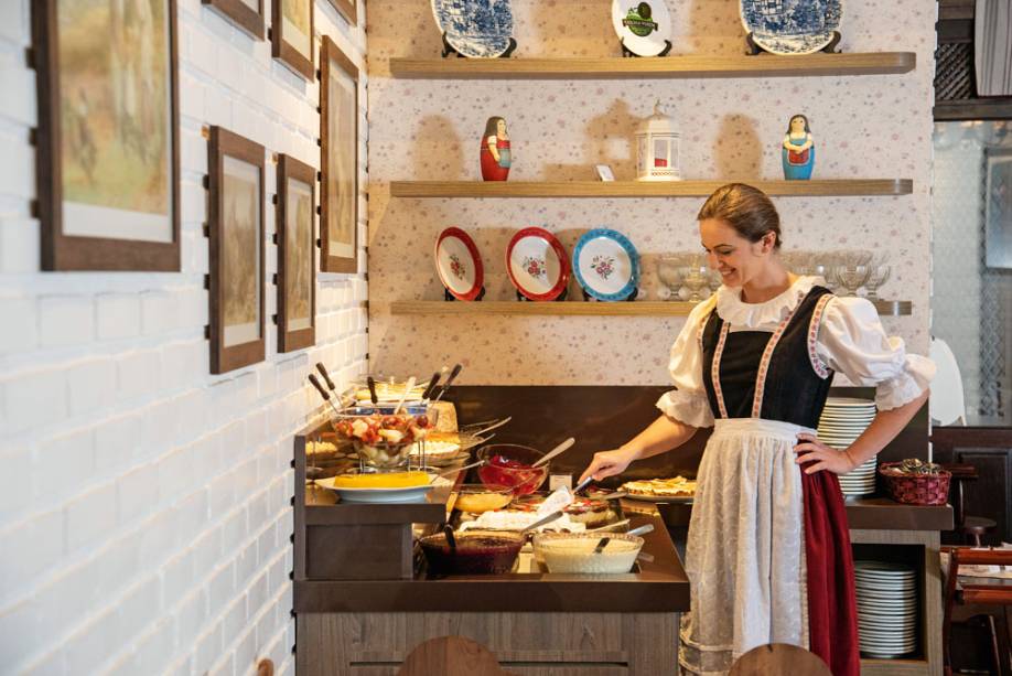 Uma das atendentes com traje típico e as sobremesas: até dez tipos de doce