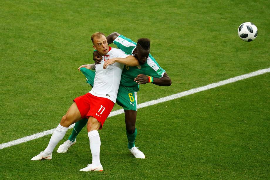 Kamil Grosicki, da Polônia, disputa uma bola com o senegalês Salif Sane