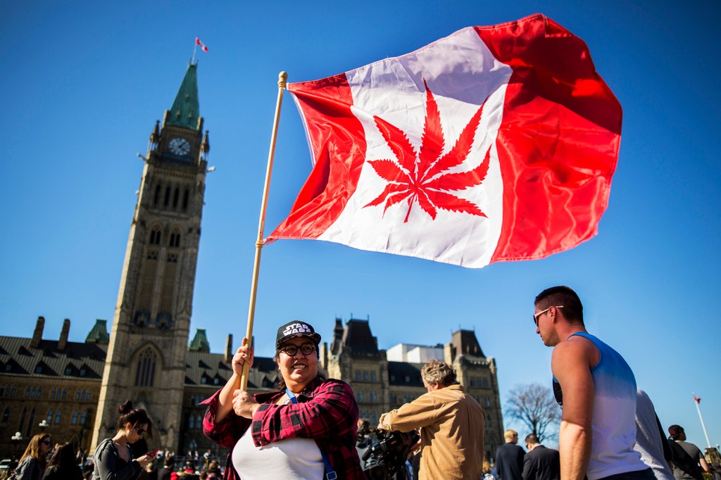 Mulher é vista com bandeira do Canadá, com uma folha de maconha ao centro, em Ottawa - 20/04/2016