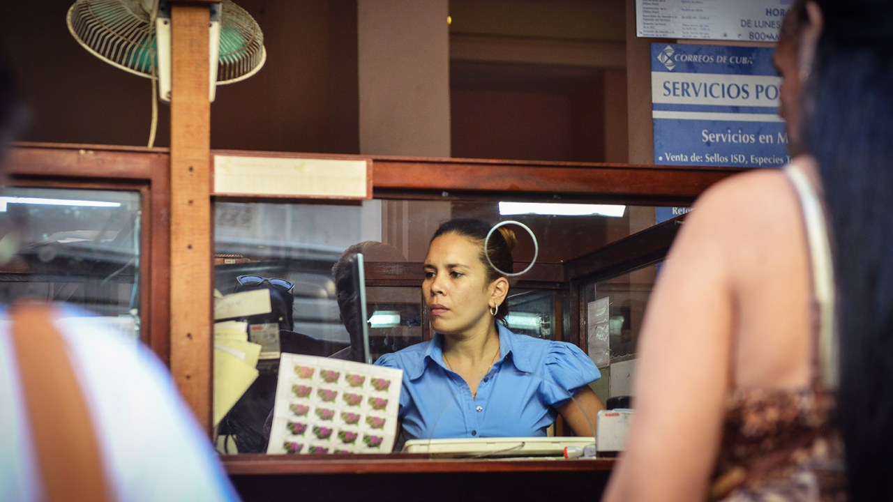 Funcionária de correio de Cuba atende clientes em Havana - 11/12/2015