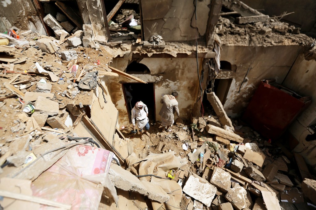 Moradores locais procuram pertences entre os escombros após ataque em Amran, no Iêmen - 25/06/2018