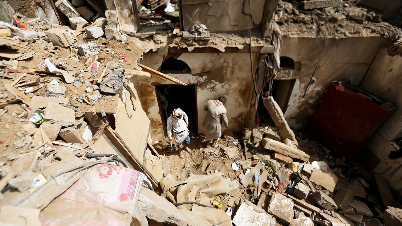 Moradores locais procuram pertences entre os escombros após ataque em Amran, no Iêmen - 25/06/2018
