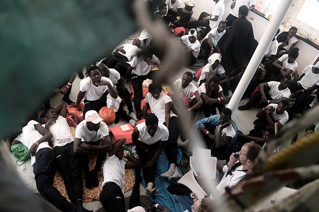 Migrantes sentam-se no convés do MV Aquarius, após resgate no Mar Mediterrâneo - 12/06/2018