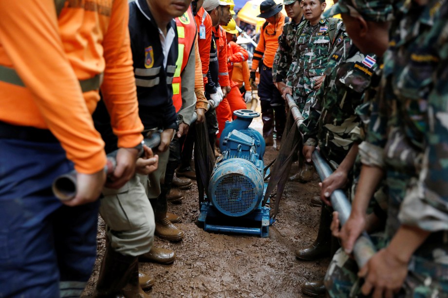 Soldados e equipes de resgate carregam uma bomba de água para o complexo de cavernas de Tham Luang durante a busca por membros de um time de futebol de crianças e seu treinador, na província de Chiang Rai, na Tailândia - 28/06/2018