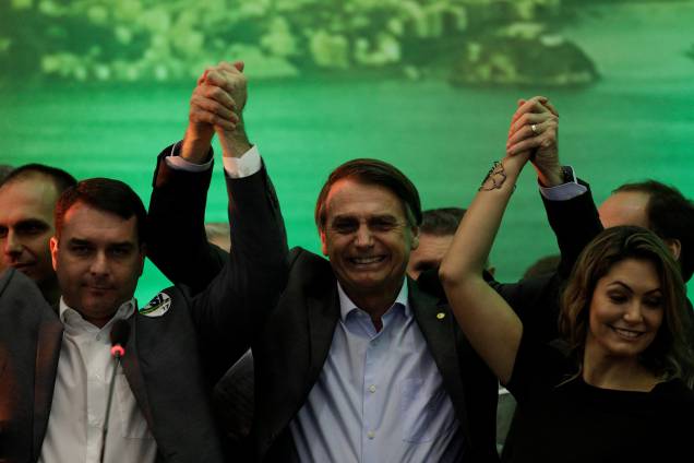 O deputado federal Jair Bolsonaro levanta as mãos com seu filho Flavio Bolsonaro e sua esposa Michelle Bolsonaro durante convenção nacional do PSL, em que foi formalizado como candidato à Presidência da República, no Rio de Janeiro - 22/07/2018