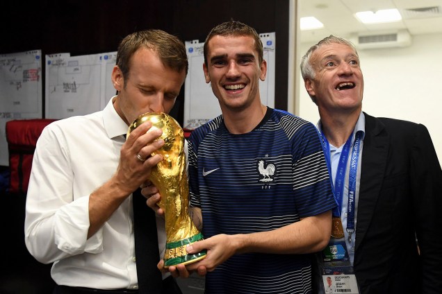 O presidente francês, Emmanuel Macron, beija a taça da Copa do Mundo nas mãos do atacante Antoine Griezmann dentro do vestiário, após a partida contra a Croácia - 15/07/2018