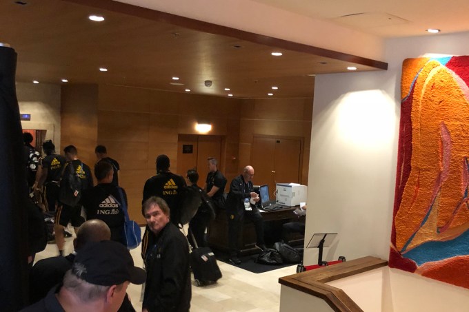 Jogadores aguardam elevador separados por cortina dos outros hóspedes do hotel