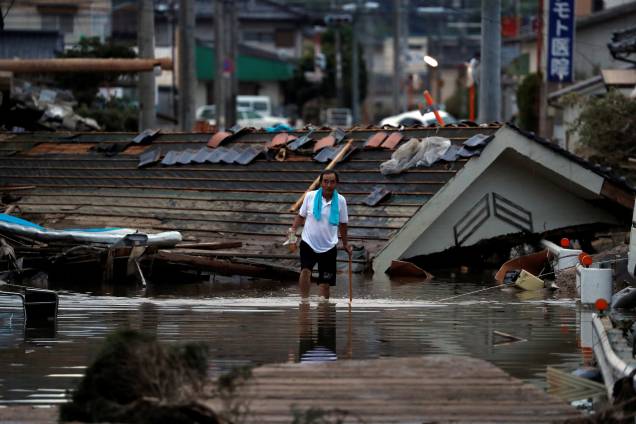 Morador caminha em frente a casas submersas e destruídas em uma área inundada na cidade de Mabi, em Kurashiki, província de Okayama, no Japão - 08/07/2018