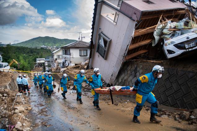 Policiais chegam para trabalhar no resgate de vítimas e retirada de destroços espalhados em uma rua destruída após inundações em Kumano, prefeitura de Hiroshima, no Japão - 09/07/2018