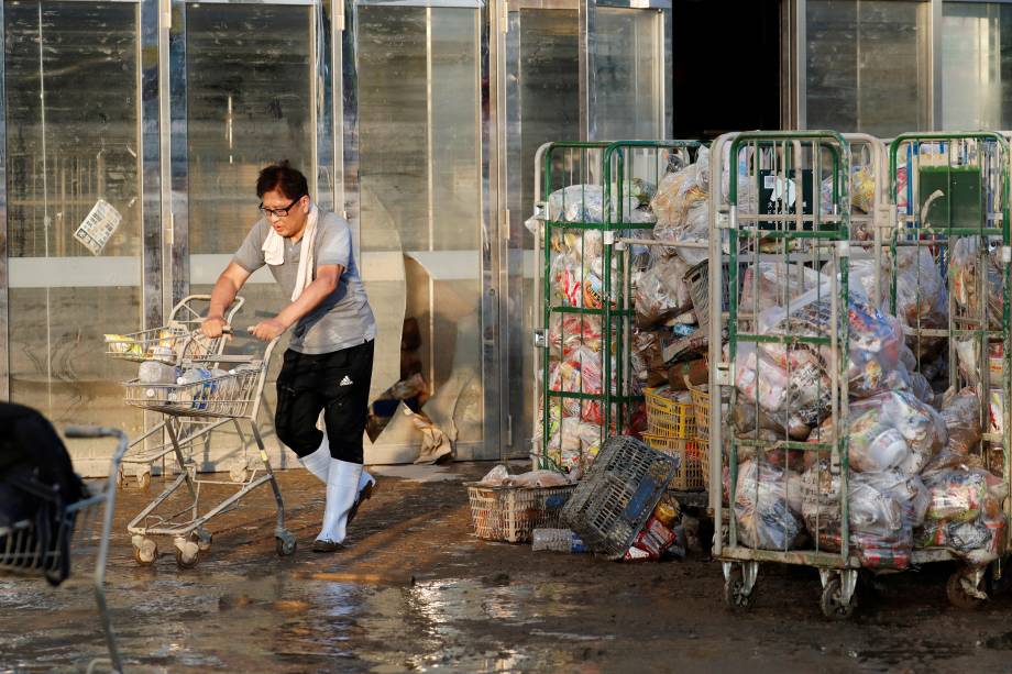 Funcionário de um supermercado empurra um carrinho, com itens enlameados, em uma área inundada na cidade de Mabi em Kurashiki, prefeitura de Okayama, no Japão - 09/07/2018