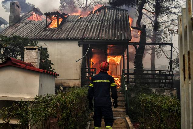 Bombeiro avista uma casa em chamas em Kineta, perto de Atenas, durante um incêndio florestal no qual 300 bombeiros, cinco aeronaves e dois helicópteros foram mobilizados para enfrentar a situação - 23/07/2018