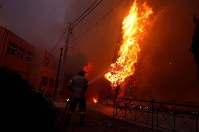 Bombeiro trabalha para conter as chamas de um incêndio florestal em Rafina, perto de Atenas, na Grécia - 23/07/2018