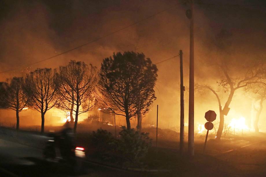 Edifícios queimam atrás de árvores na cidade de Mati, na Grécia. As autoridades regionais declararam estado de emergência nas partes leste e oeste da área metropolitana de Atenas, quando os incêndios se espalharam por florestas de pinheiros e assentamentos à beira-mar em ambos os lados da capital grega - 23/07/2018