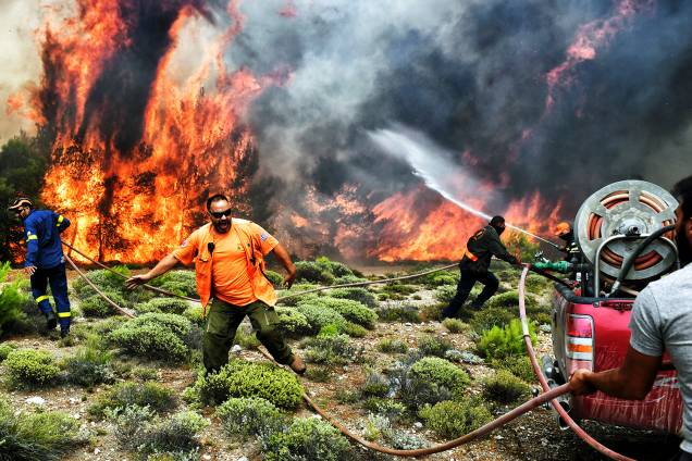 Bombeiros e voluntários trabalham no combate às chamas, durante incêndio florestal no vilarejo de Kineta, próximo de Atenas, Grécia - 24/07/2018
