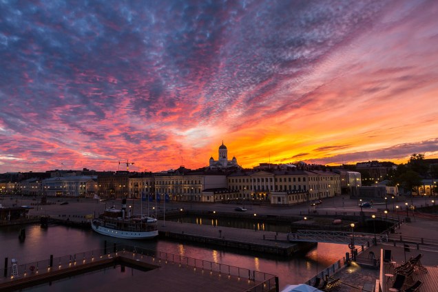 O pôr do sol é visto atras da Catedral Luterana de Helsinque, na Finlândia