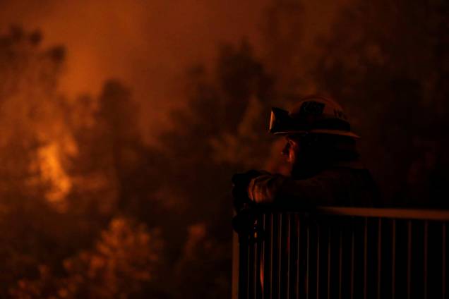O bombeiro Zach Hallums é visto enquanto seus companheiros lutam contra o incêndio Carr abaixo de um cânion ao oeste de Redding - 27/07/2018