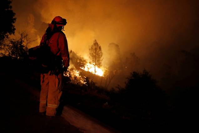 Bombeiro observa as chamas enquanto o fogo avança em direção a casas no oeste da cidade de Redding, na Califórnia - 27/07/2018