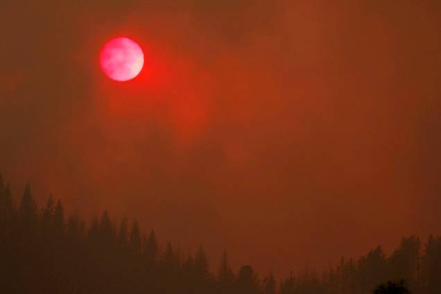 O sol fica rosado enquanto a densa fumaça do incêndio florestal Carr sobre das árvores, na Califórnia - 27/07/2018