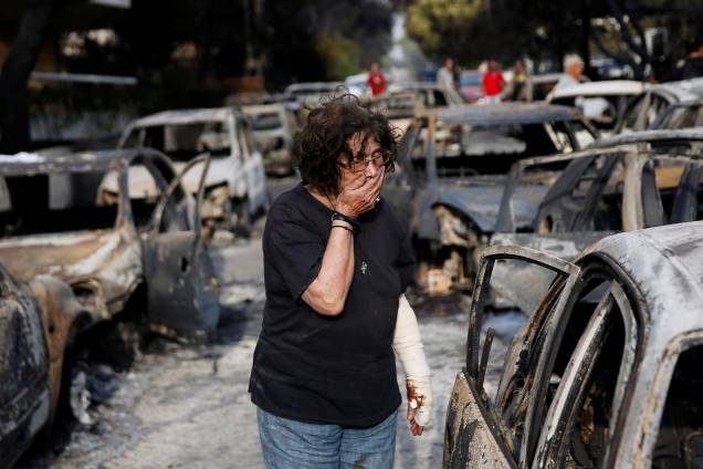 Mulher chora enquanto tenta encontrar seu cachorro, depois de um incêndio na aldeia de Mati, perto de Atenas, na Grécia - 24/07/2018