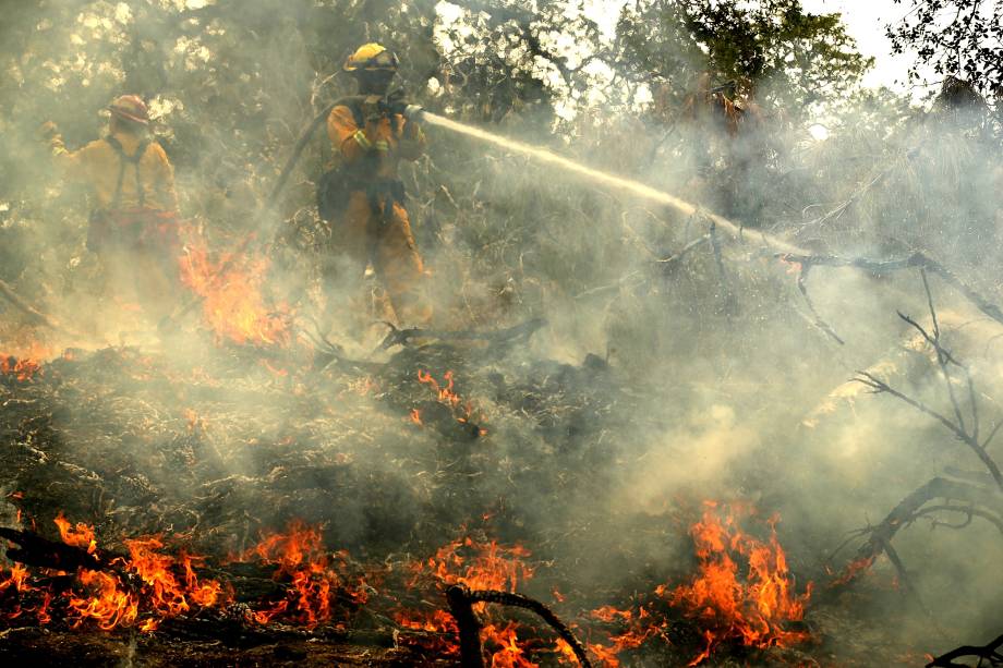 Bombeiro usa uma mangueira na tentativa de extiguir focos de incêndio em Redding, na Califórnia - 28/07/2018