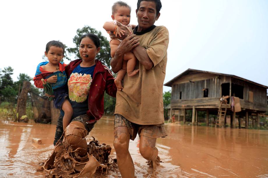 Pais carregam seus filhos após deixarem sua casa durante enchente provocada pelo rompimento da represa de Xepian-Xe Nam Noy na província de Attapeu, Laos - 26/07/2018