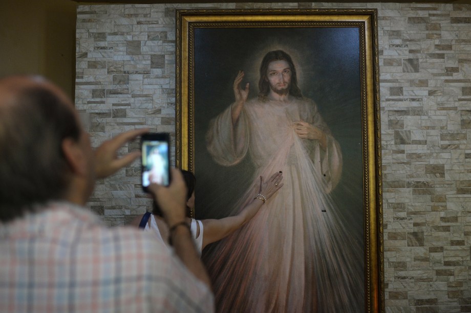 Fiéis católicos rezam diante de uma imagem de Jesus Cristo, atingida por balas durante um ataque das forças do governo Daniel Ortega à igreja da Divina Misericórdia em Manágua, na Nicarágua - 20/07/2018