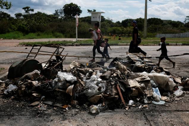 Venezuelanos passam por pertences e barracas queimadas por civis brasileiros no controle de fronteira de Pacaraima, em Roraima - 19/08/2018 Venezuelanos passam por pertences e barracas queimadas por civis brasileiros no controle de fronteira de Pacaraima, em Roraima - 19/08/2018