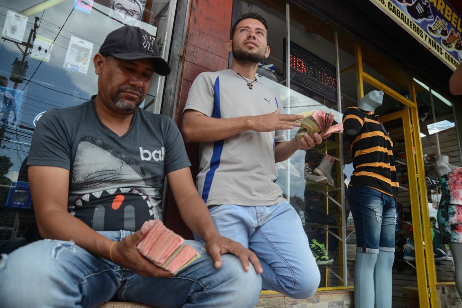 Cambistas exibem maço de dinheiro. 1 real equivale a 300 bolívares