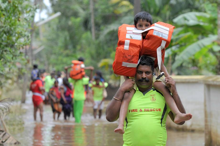 Bombeiro carrega uma criança nos ombros durante as operações de resgate na vila de Annamanada, distrito de Thrissur, no estado de Kerala, no sul da Índia - 19/08/2018