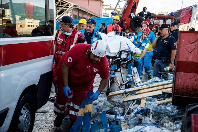 Corpo é carregado por equipes de resgate enquanto aguardam a chegada de ambulância, após queda de ponte em Gênova, na Itália - 14/08/2018