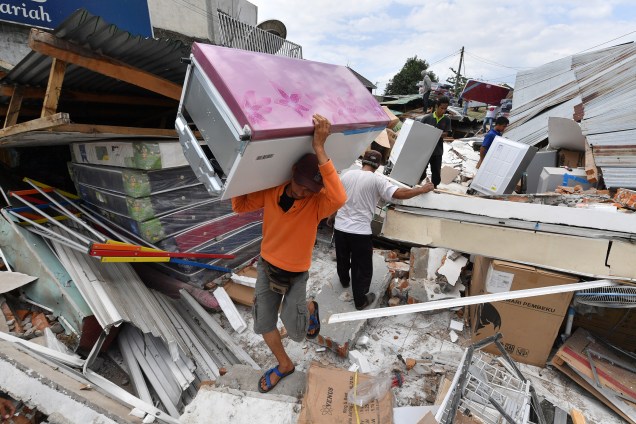 Homem carrega uma geladeira das ruínas de uma loja de eletrodomésticos em Bangsal, no norte de Lombok, três dias depois da área ter sido atingida por um terremoto - 08/08/2018