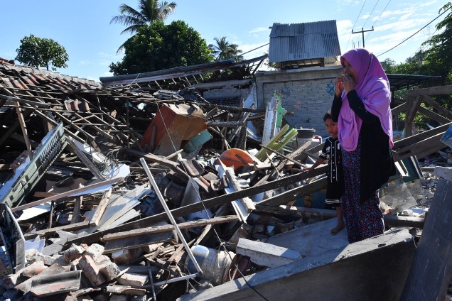 Mulher e um menino observam enquanto homens limpam os destroços de casas danificadas por um terremoto em Menggala, no norte de Lombok, três dias depois que o terremoto atingiu a ilha que pertence à Indonésia - 08/08/2018