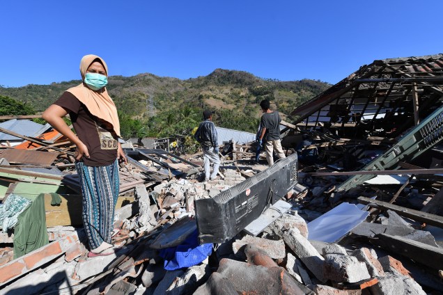 Pessoas procuram por seus pertences nos escombros das casas danificadas em Menggala, no norte de Lombok, três dias depois que a área foi atingida por um terremoto na Indonésia - 08/08/2018