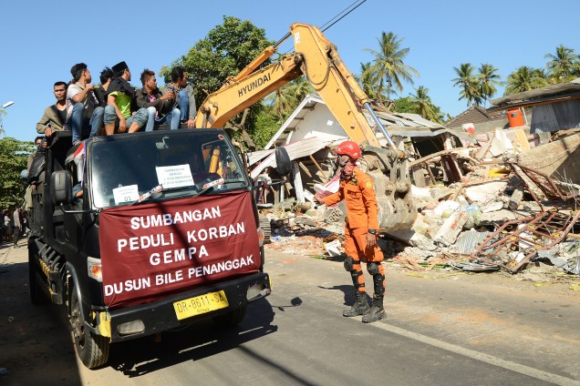 Moradores ficam sobre um caminhão de resgate durante busca por vítimas nos escombros de prédios desmoronados após terremoto em Sigar Penjalin, no norte de Lombok, na Indonésia - 08/08/2018
