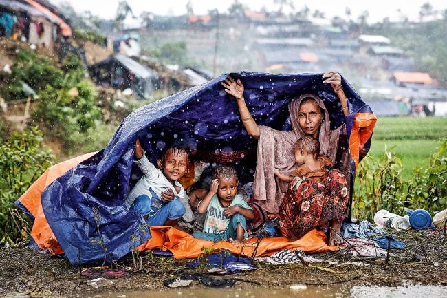 Família de rohingyas protege-se da chuva, em Bangladesh