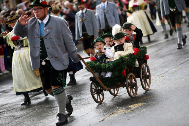 Homem vestido com roupas tradicionais dos bávaros carrega seus filhos em uma carrocinha durante um desfile da Oktoberfest 2018, em Munique, na Alemanha - 23/09/2018