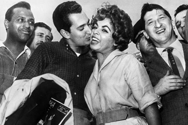 O cantor e compositor americano Neil Sedaka beija a cantora brasileira Ângela Maria, observado pelo cantor Carlos Gonzaga em São Paulo - 08/11/1959 O cantor e compositor americano Neil Sedaka beija a cantora brasileira Ângela Maria, observado pelo cantor Carlos Gonzaga em São Paulo - 08/11/1959