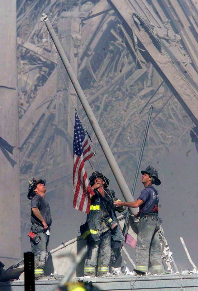 Bombeiros levantam uma bandeira dos Estados Unidos em meio aos escombros do World Trade Center após ataque terrorista - 11/09/2001