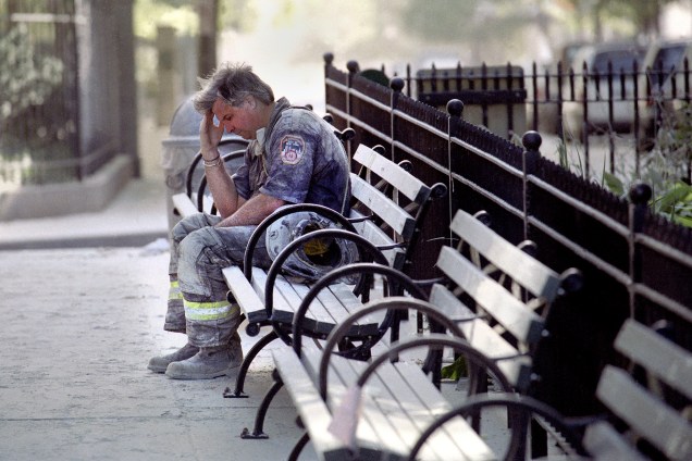Bombeiro faz uma pausa em um banco duante as operações de resgate após o colapso das torres gêmeas do World Trade Center alvo de um ataque terrorista - 11/09/2001