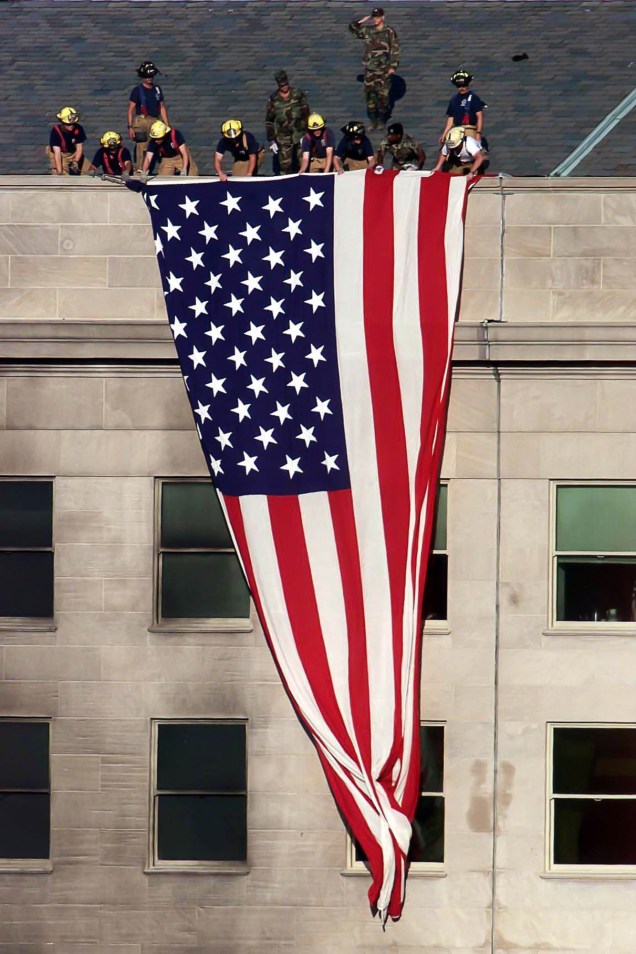 Bombeiros e militares estendem uma bandeira dos Estados Unidos sobre o prédio do Pentágono a poucos metros da área danificada pelo ataque  terrorista - 11/09/2001
