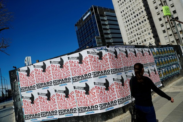 Pedestre caminha próxima de cartazes fixados em muro, durante greve geral em Buenos Aires, capital da Argentina - 25/09/2018