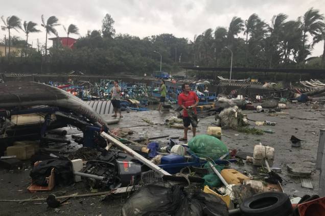 Moradores caminham entre os destroços do porto de pesca de Shang Wu, no condado de Taitung, leste de Taiwan - 15/09/2018
