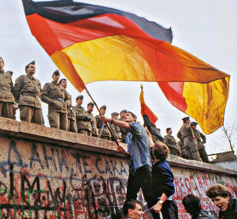 Manifestantes vistos junto a soldados no Muro de Berlim em novembro de 1989