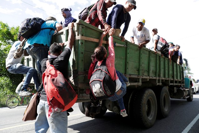 Imigrante hondurenha é puxada para conseguir subir em um caminhão que toma rumo aos Estados Unidos, em direção à fronteira mexicana, em Chiquimula, na Guatemala - 24/10/2018