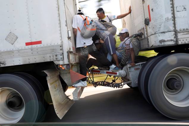 Imigrantes são vistos entre os eixos de um caminhão na estrada para Mapastepec de Huixtla, México, enquanto seguem para os Estados Unidos - 24/10/2018