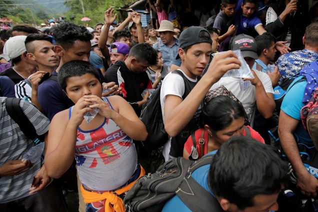 Imigrantes participantes de caravana com destino aos Estados Unidos chegam na fronteira de Honduras com a Guatemala e recebem água dos policiais - 15/10/2018