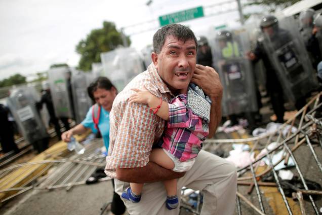 Imigrante hondurenho protege seu filho depois que outros imigrantes, parte de uma caravana que tentava chegar aos Estados Unidos, invadiram um posto fronteiriço em Ciudad Hidalgo, México - 20/10/2018