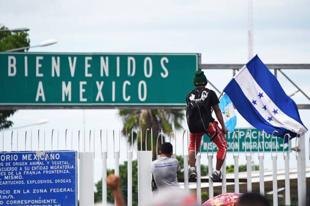 Migrante hondurenho é visto com bandeira, próximo da fronteira entre a Guatemala e o México, no território de Ciudad Tecun Uman - 19/10/2018
