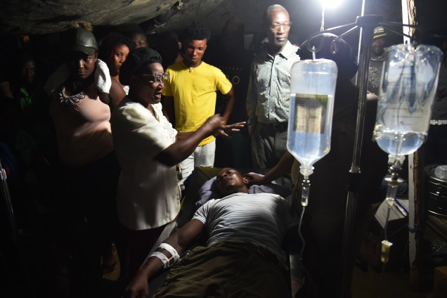 Mulher ora por homem ferido após terremoto no Hospital Imaculada Concepção em Port-de-Paix, Haiti - 07/10/2018