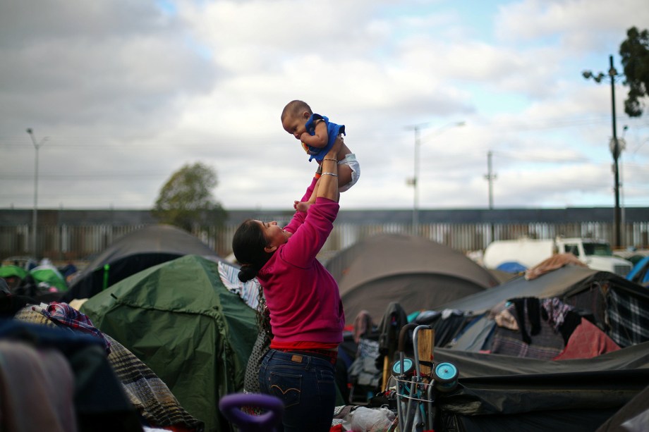 Migrante ergue bebê em acampamento montado na fronteira entre o México e os Estados Unidos, na cidade de Tijuana - 28/11/2018